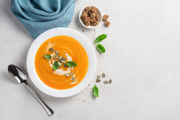 Pumpkin soup with carrots and cream on a gray background with space for copying.