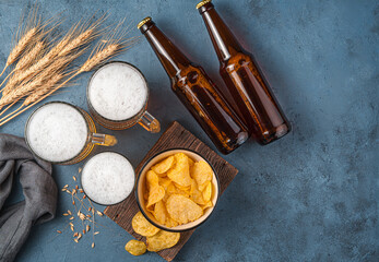 Beer, chips and wheat spikelets on a dark blue background.
