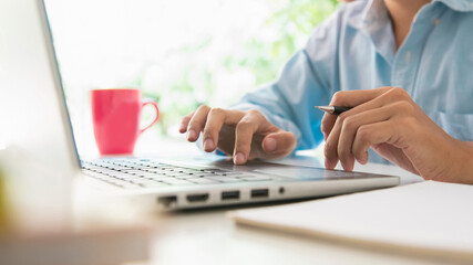 Close up, people hand using a pencil writing notebook paper learning and researching course tutor education, online on technology personal computer laptop with coffee cup