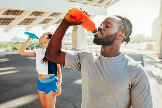 Sporty runners couple drinking energy drink after running