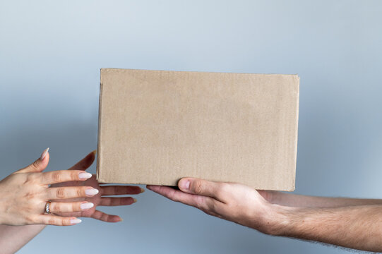 Box in the hands of two people on a gray background.