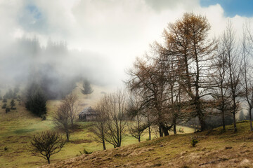 Autumn landscape high in the mountains. Clouds in the sky over mountain peaks. Old abandoned house in the mountains