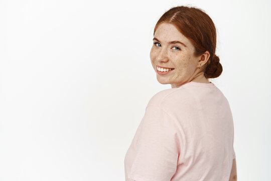 Image of young redhead girl smiling, turn head at camera with positive, happy face expression, looking cheerful, standing in summer t-shirt against white background