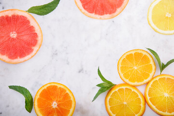 Summer tropical juice concept with lemon, grapefruit and orange on luxury marble kitchen table. Flat lay. Fresh smoothie beverage menu background. Top view of colorful fruit slices with citrus leaf 