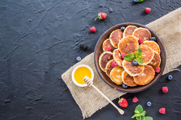 A healthy breakfast of cheese pancakes, berries, and honey. Creative atmospheric decoration