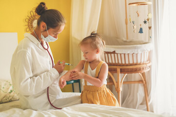 A nurse doctor makes an injection to a child's baby at home in a bedroom, an examination of a baby...
