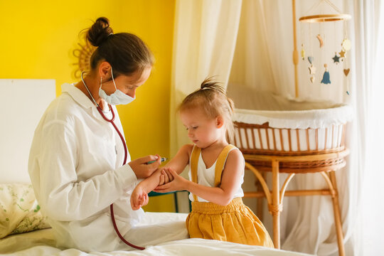 A nurse doctor makes an injection to a child's baby at home in a bedroom, an examination of a baby at home, a patronage. Regular medical examination of babies, preventive vaccinations