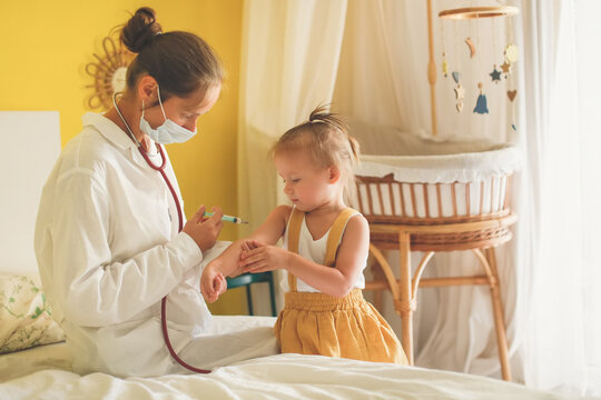 A nurse doctor makes an injection to a child's baby at home in a bedroom, an examination of a baby at home, a patronage. Regular medical examination of babies, preventive vaccinations