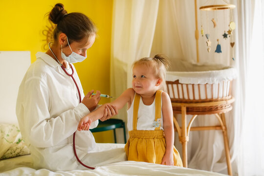 A nurse doctor makes an injection to a child's baby at home in a bedroom, an examination of a baby at home, a patronage. Regular medical examination of babies, preventive vaccinations