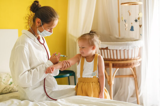 A nurse doctor makes an injection to a child's baby at home in a bedroom, an examination of a baby at home, a patronage. Regular medical examination of babies, preventive vaccinations