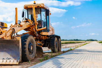 Road grader - heavy equipment for road construction and earthworks. Leveling and improvement of the ground surface. Construction of roads and transport communications.
