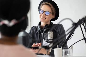 Young and confident European woman recording a podcast in a recording studio, woman creating audio content or recording radio interviews, business woman radio host recording commercials or