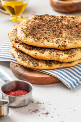 Homemade flatbread with herbs and sumac on a gray concrete background.