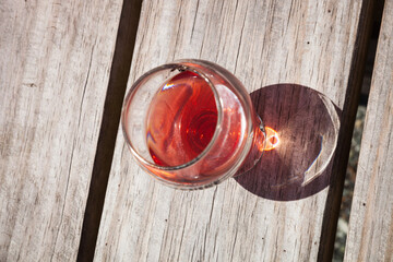 Glass of Rose Wine or cider on a wooden table with the shadow of the glass, closeup from top