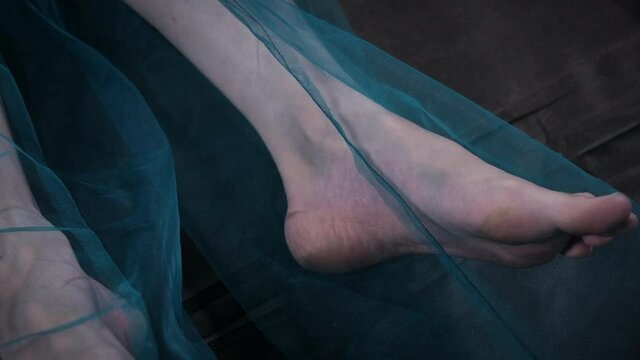 Video of lying female bare foot in blue fabric