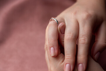 shows a large size wedding ring on a finger with a place for text on a pink background