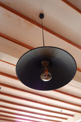 Classic lamp that is hung against the background of the roof of the room. Modern interior design for cafe