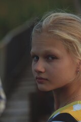 Naklejka premium Portrait of blonde teenage girl outdoors on the bridge. The blonde girl looked back at the camera. The face of a beautiful blonde girl.
