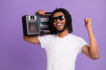 Portrait of attractive cheerful guy carrying tape player having fun rest isolated over bright violet purple color background