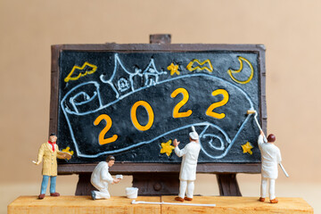 Miniature people worker team painting number 2022 on black board, Happy new year concept