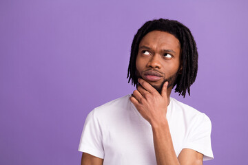 Photo of young minded afro american thoughtful man look empty space hand chin isolated on violet...