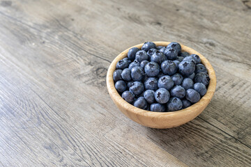 Fresh blueberries in a bamboo bowl isolated on a wooden table. Healthy diet high in antioxidants and fresh fruit healthy eating concept.