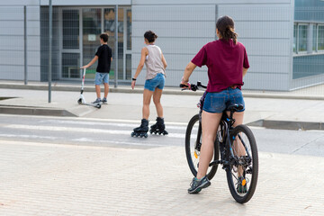 People ride bicycles and roller skates on the street.