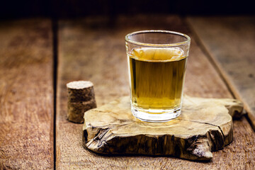 glass of distilled alcoholic beverage on wooden background with copy space for text. Call for rum or cachaça