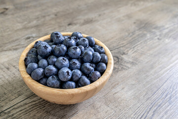 Blueberries in a bamboo bowl close up on a wooden table. Healthy diet high in antioxidants and fresh fruit healthy eating concept.