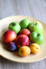 Wooden bowl with various colorful fruit. Selective focus.