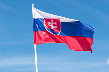 Slovak flag waving in wind and sunlight. Flag of Slovakia on blue sky background. 