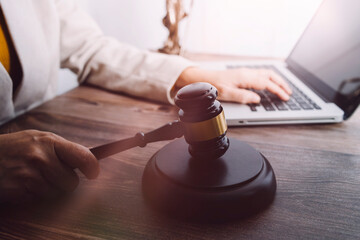 Justice and law concept.Male judge in a courtroom with the gavel, working with, computer and docking keyboard, eyeglasses, on table in morning light