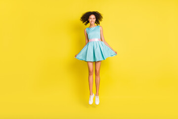Full length photo of cool curly hairdo millennial lady wear teal dress sneakers isolated on yellow color background © deagreez