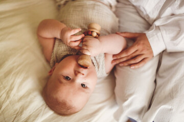 European Baby 3 4 months old with rattle wooden toy, top view