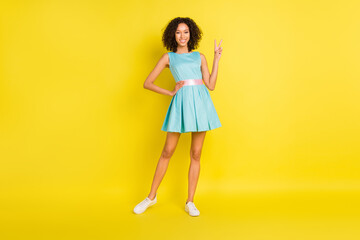 Full size photo of young dark skin woman good mood show v-sign cool hello isolated on yellow color background