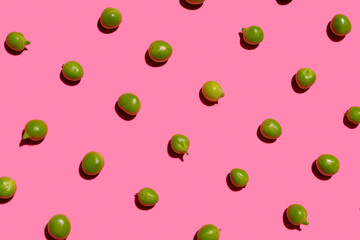 Pattern of green peas flat laid against pink background