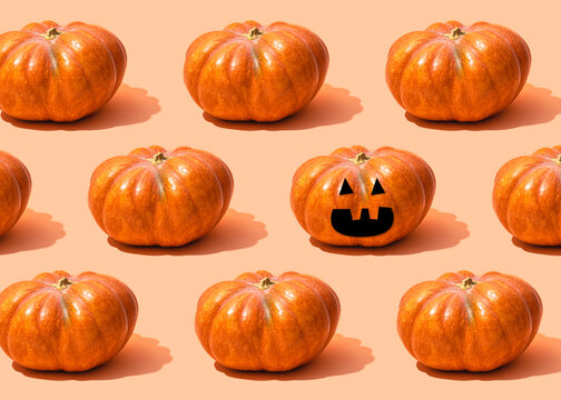 Pattern of raw pumpkins surrounding single jack-o-lantern