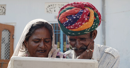 South Asian elder couple in traditional Rajasthan Indian clothing watching a video on a laptop