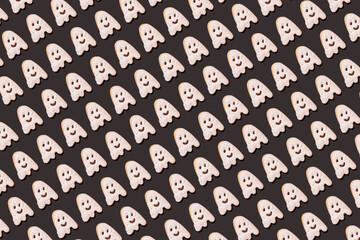 Pattern of ghost-shaped chocolate cookies flat laid against black background