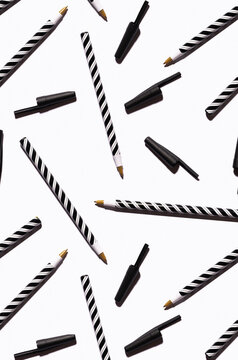 Pattern of black and white striped pens flat laid against white background