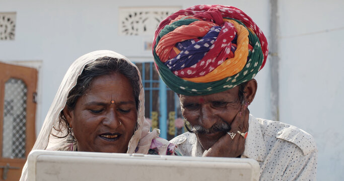 South Asian Elder Couple In Traditional Rajasthan Indian Clothing Watching A Video On A Laptop