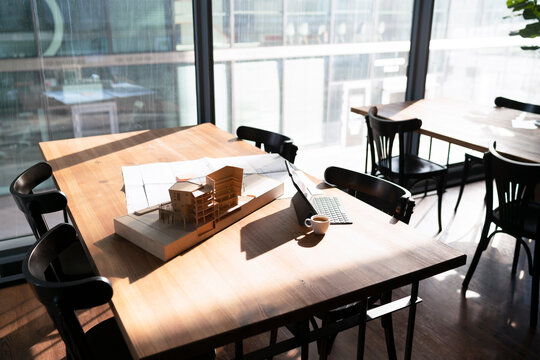 Architectural model and blueprint with laptop on table at office cafeteria