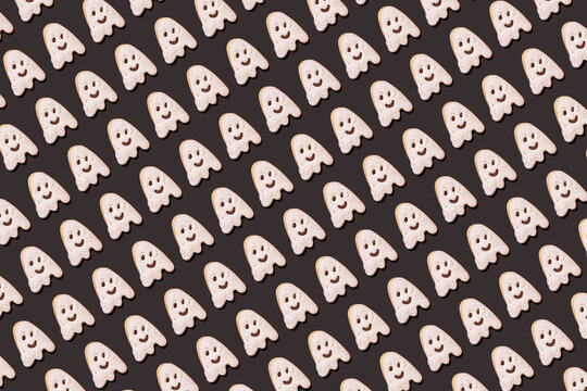 Pattern of ghost-shaped chocolate cookies flat laid against black background