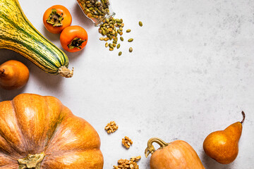 Autumnal background with pumpkins, pears, walnuts, pumpkin seeds, persimmons and copy space