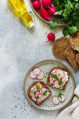 Healthy toasts of rye whole-grain bread with sunflower, flax and pumpkin seeds with cottage cheese (goat or ricotta), olive oil, fresh radishes, parsley and black and white sesame