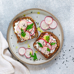 Healthy toasts of rye whole-grain bread with sunflower, flax and pumpkin seeds with cottage cheese (goat or ricotta), olive oil, fresh radishes, parsley and black and white sesame - 445413593