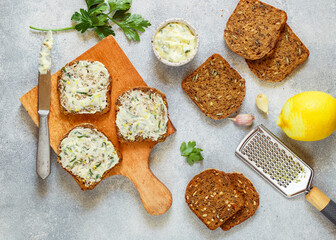 Healthy toasts of rye whole-grain bread with sunflower seeds, flax and pumpkin with butter with lemon zest, garlic and parsley. Gourmet appetizer for soup. Selective focus, top view