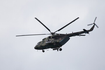 Khaki camouflage Soviet military helicopter with red star on board fly on gray sky background, bottom up view