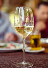 Glass on a high thin leg with white wine in a restaurant