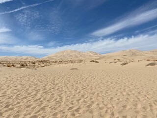 Desert landscape with high dunes and wispy clouds